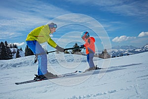 Instructor in skiing school glide backwards teach child to ski photo