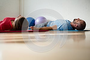 Instructor and student exercising while lying on mat in studio