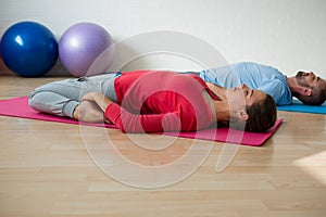 Instructor with student practicing reclined hero pose in studio