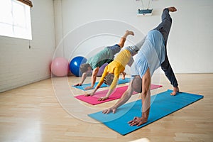 Instructor with students practicing downward facing dog pose with feet up