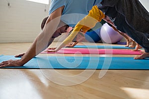 Instructor with students practicing downward facing dog pose at yoga studio