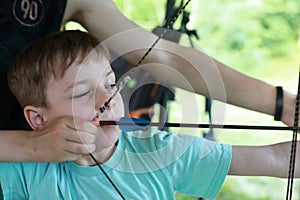 Instructor teaches child how to shoot bow