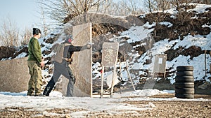 Instructor teaches student tactical gun shooting behind cover or barricade