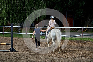 An instructor teaches a teenage girl horse riding, equestrian sports