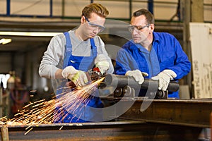 Instructor teaches trainee how to use an angle grinder photo