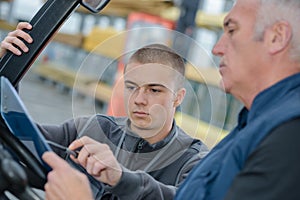 Instructor teaching apprentice how to drive heavy construction vehicle