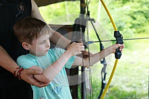 Instructor teaching boy to shoot bow