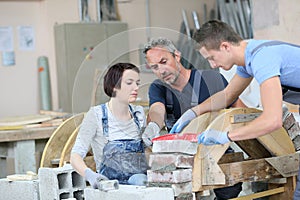Instructor teaching trainees laying bricks