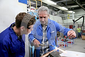 Instructor teaching young apprentice mettallurgy