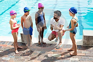Instructor training children at poolside