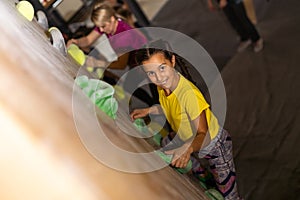 Instructors helping children climb wall in gym