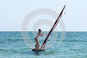 Instructors teach the child to ride windsurfing