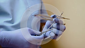 The instrument in the hands of the doctor. Close up of unrecognizable hands of medical doctor, surgical scissors