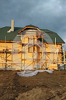 Insulation of the house with facade bricks, construction of a new house and scaffolding near the walls