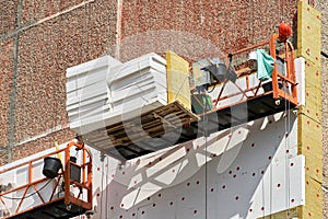 Insulation of a multi-storey building from the outside. Two construction bassinets with facade insulation at a height of