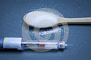 Insulin pen along with a tablespoon of white sugar