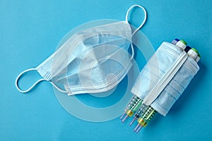 Insulin syringe pens wrapped with medical masks on a blue background