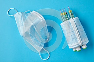 Insulin syringe pens wrapped with medical masks on a blue background