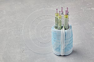Insulin syringe pens wrapped in medical masks on a gray concrete background