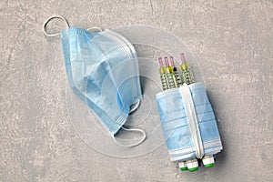 Insulin syringe pens wrapped with medical masks on a gray concrette background