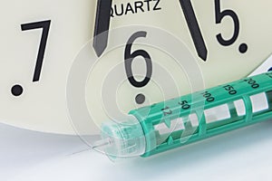 Insuline syringe, the clock shows the time of the medication photo