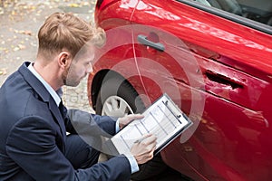 Insurance Agent Examining Car After Accident