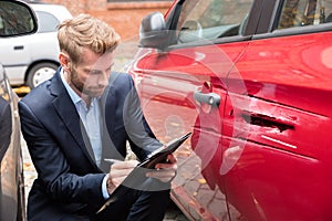 Insurance Agent Examining Car After Accident