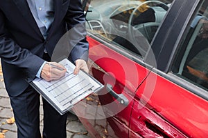 Insurance Agent Examining Car After Accident