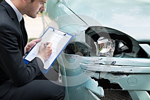 Insurance agent examining car after accident
