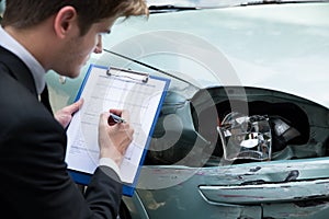 Insurance agent examining car after accident photo