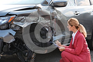 Insurance agent filling claim form near broken car