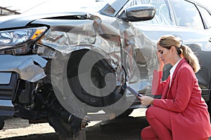Insurance agent filling claim form near broken car