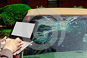 Insurance agent filling Insurance claim form on laptop after car accident, windshield crash
