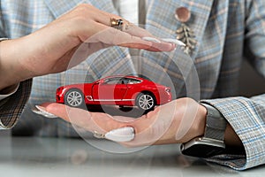 Insurance agent holding red car toy as vechicle insurance