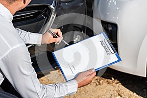 Insurance Agent Inspecting assessed Damaged Car checking and signing on report insurance claim form process after accident