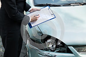 Insurance agent inspecting car after accident