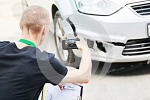 Insurance agent or loss adjuster inspecting damaged automobile