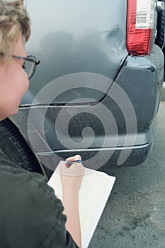 Insurance agent, middle-aged woman, conducts pre-insurance inspection of car