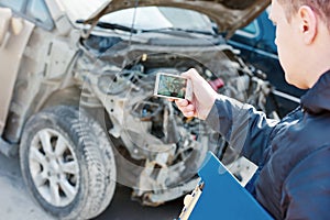 Insurance agent photographing car damage for claim form