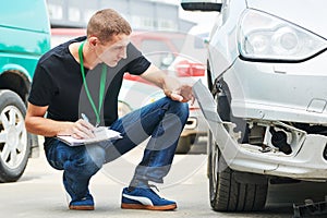 Insurance agent recording car damage on claim form