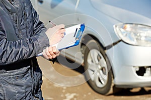 Insurance agent recording car damage on claim form