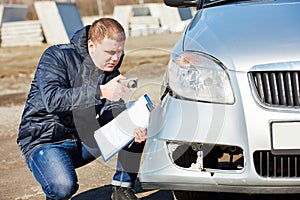 Insurance agent recording car damage on claim form