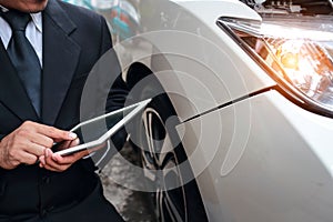 Insurance agent using tablet for insurance claim with damaged car on accident