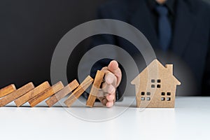 Insurance agents or family leaders are using hands to prevent Dominos from falling into the house.