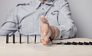Insurance concept. Businessman hand closeup protecting domino pieces from falling. Economic crisis and business failure