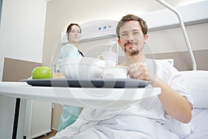 insurance concept female patient enjoying meal in hospital bed