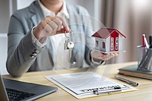 Insurance concept the real estate representative holding a house key on the right hand and the house model on the left hand