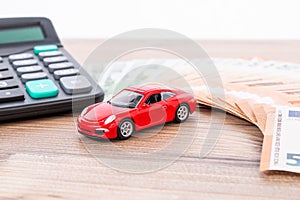 Insurance, loan and buying car concept. Red car and euro banknotes. Calculator, euro money and red car. Copy space for text.