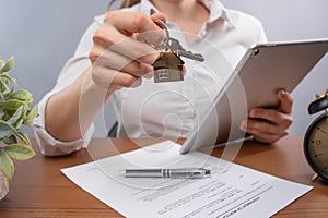 Insurance mortgage broker using laptop and giving key and home shaped keychain after signing mortgage application form. Concept of