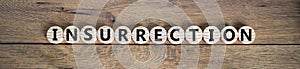 Insurrection symbol. Wooden circles with the word `insurrection`. Beautiful wooden background, copy space. Business and photo